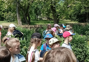 Na zdjęcu znajdują się uczniowie, spacerujący po ogrodzie na terenie skansenu