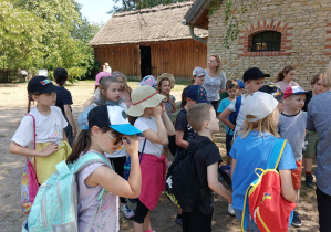 Na zdjęcu znajdują się uczniowie, spacerujący po ogrodzie na terenie skansenu