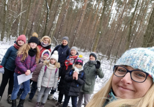 Na fotografii widać uczniów i opiekunów, którzy brali udział w rajdzie. W tle las pokryty śniegiem.