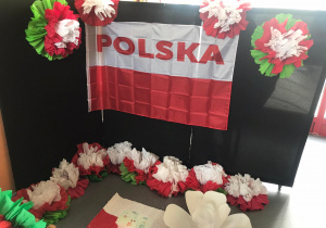 Na zdjęciu widać dekorację - flagę Polski oraz kolorowe kwiaty.