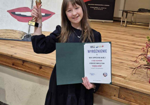 Dziewczynka uśmiechnięta trzymająca w rękach puchar i dyplom