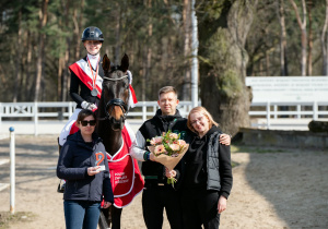 Dziewczynka siedząca na koniu wraz z rodzicami po wygranej w zawodach