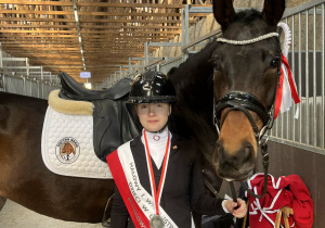 Uśmiechnięta i szczęśliwa dziewczynka wraz ze swoim koniem pozująca do zdjęcia podczas zawodów