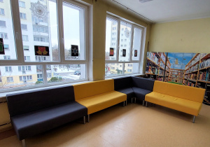 Kanapy koloru szarego i żółtego na drugim piętrze, ustawione pod oknem